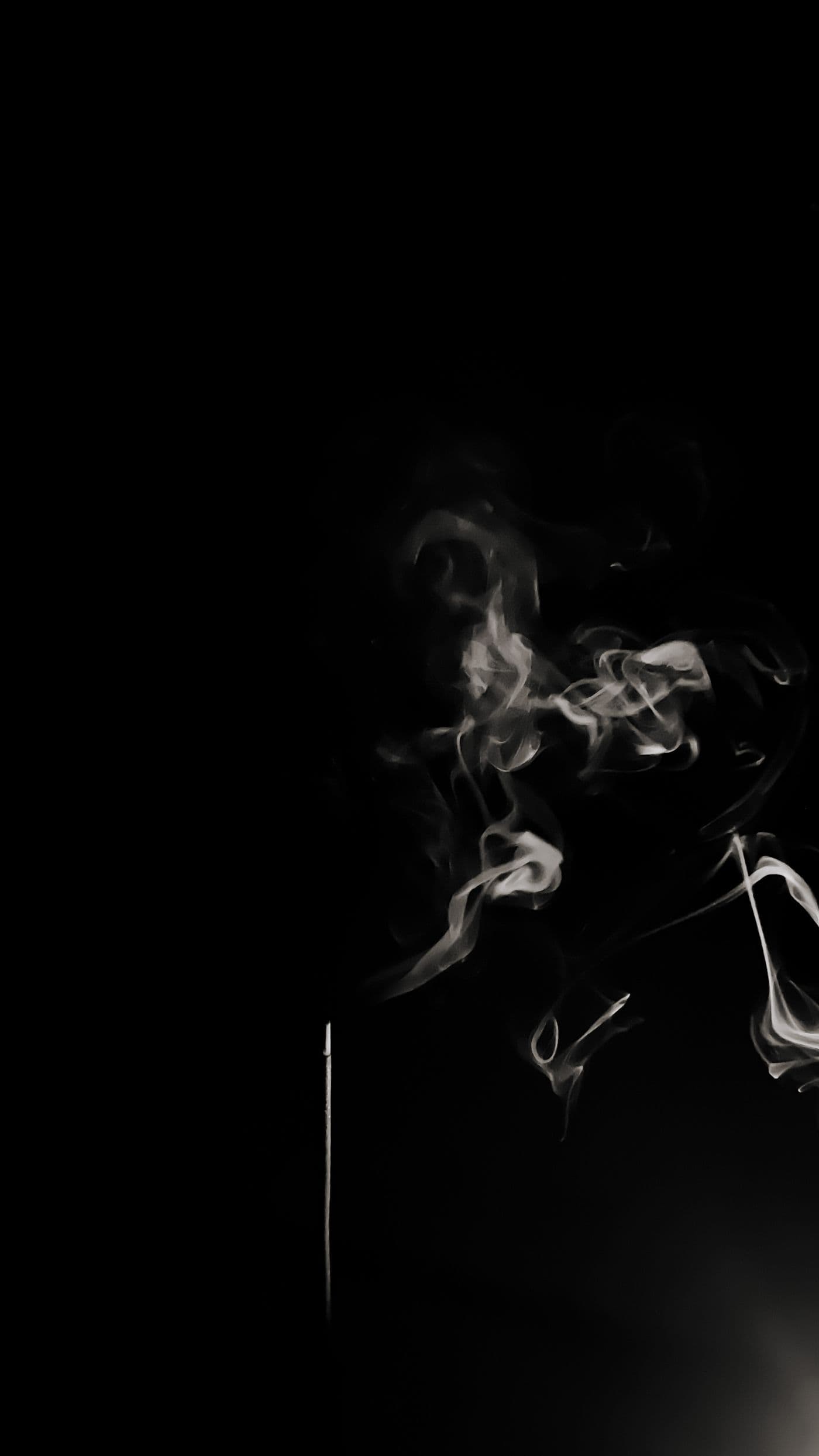 A slow drift of smoke crossing a dark neutral background